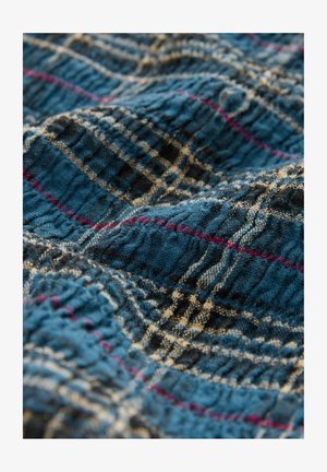 Tessuto blu texture con un motivo a quadri arricchito da linee rosa e avorio, creando un effetto stratificato e stropicciato. Materiale morbido e leggero.