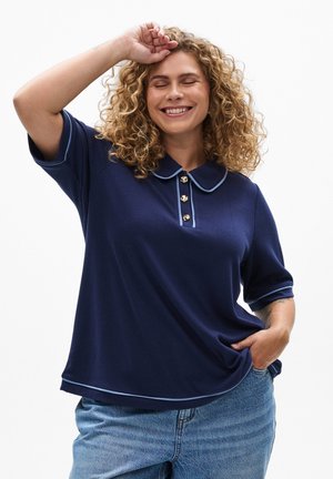 Polo blu navy a maniche corte, con colletto e bordi in contrasto di azzurro chiaro, e bottoni dorati. Indossato con jeans di denim a vita alta.