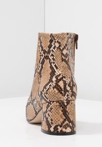 Botas tobilleras de piel de serpiente marrón con un acabado texturizado, que presentan un tacón cuadrado y un cierre con cremallera en la parte trasera.