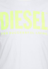 Bílý tričko s výrazným, neonově žlutým textem, který zní "DIESEL PRO ÚSPĚŠNÝ ŽIVOT", s hladkým bavlněným povrchem.