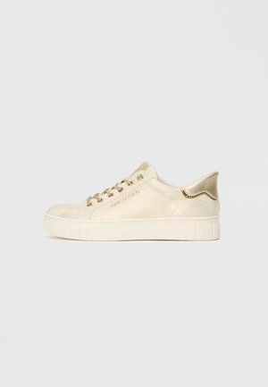 Beige Wildleder-Sneaker mit metallisch goldenen Akzenten, ausgestattet mit einem gepolsterten Kragen, Schnürverschluss und strukturiertem Gummi-Schuhsohle.