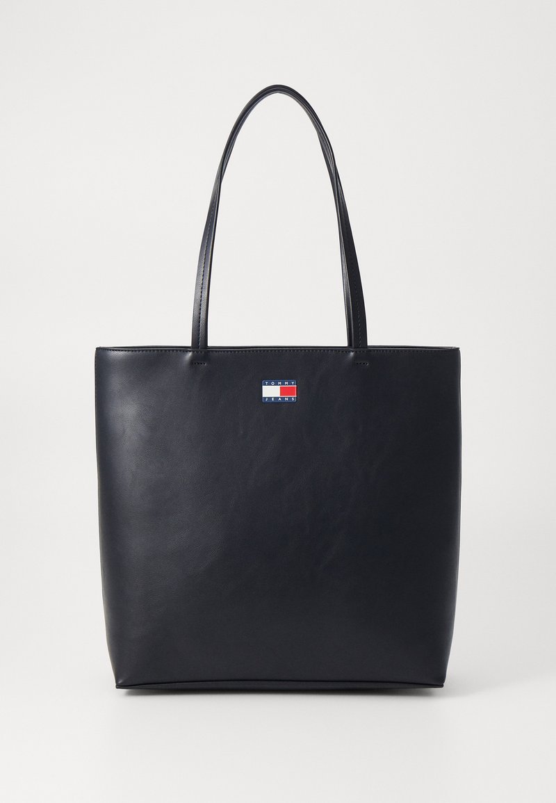 Saco tote em pele preta com textura suave, forma retangular e duas alças. Apresenta um pequeno logotipo multicolorido na frente.