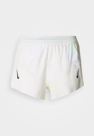 Baltos sportinės kelnės, pagamintos iš lengvos medžiagos. Kairėje pusėje yra juodas Nike logotipas, o šonuose – perforuoto dizaino detalės.