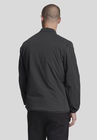 Giacca leggera nera con una texture liscia, retro senza caratteristiche e dal design semplice, adatta per un abbigliamento casual.