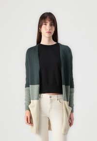 Largo cárdigan hecho de tela suave, con un degradado de verde oscuro a beige claro. Tiene un frente abierto, mangas largas y dos bolsillos delanteros.
