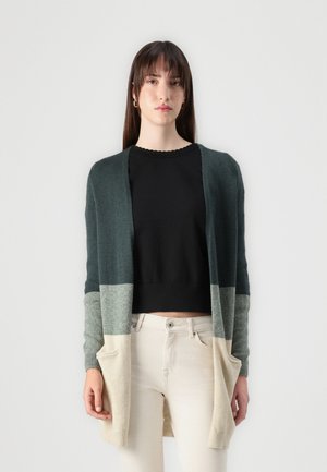 Lang cardigan laget av mykt stoff, med en gradient fra mørkegrønn til lys beige. Den har åpen front, lange ermer og to framlommer.