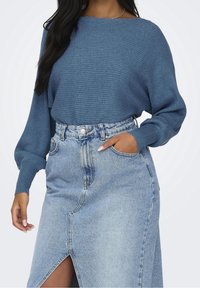 Blå randig stickad tröja med bred båtkrage, kombinerad med en ljusblå denimkjol med en frontslits och femfickdesign.