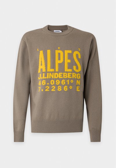 Pull marron à col rond avec texte jaune "ALPES," "J.LINDEBERG," et coordonnées 46.0961° N 7.2286° E à l'avant.