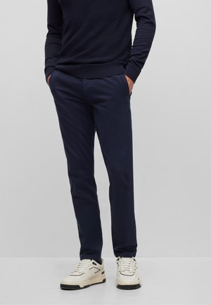 Marineblauwe chino's van glad katoen, met een slim fit en zijzakken. Draagt met een donkere trui en witte sneakers.