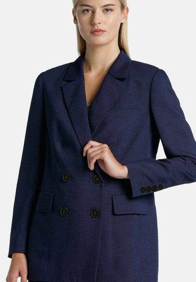 Navy blue, double-breasted blazer with a textured fabric, featuring large front buttons, notched lapels, and side pockets.