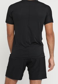 Black athletic outfit consisting of a short-sleeve shirt and shorts. The fabric features a textured design with a smooth finish.