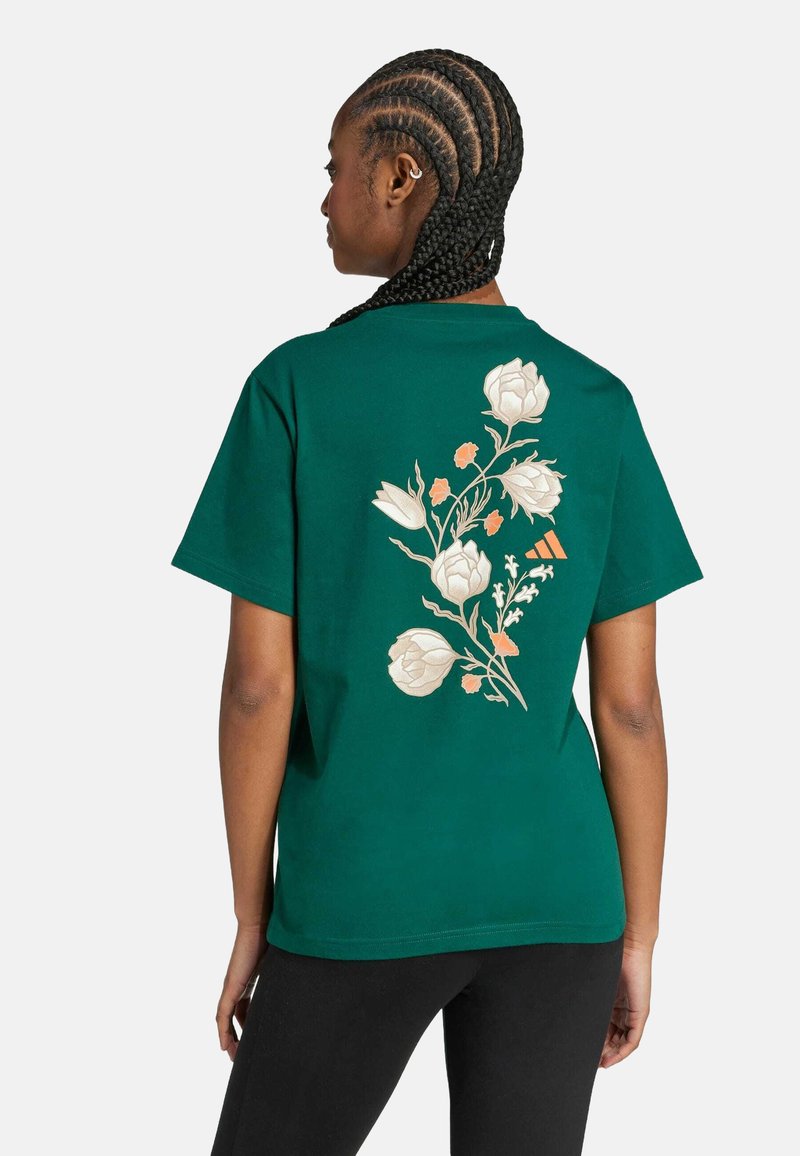 Camiseta de algodón verde con bordado floral en blanco y naranja en la parte posterior. Mangas cortas y corte relajado.