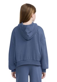 Hanorac scurt, albastru, dintr-un material moale, cu glugă, mâneci largi, tiv cu nervuri și detalii de cusătură pe spate. Asortat cu pantaloni potriviți.