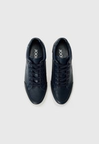 Mørkeblå sneakers laget av lær med teksturerte og glatte paneler, med såle av hvit gummi og seks par hull for snøring.