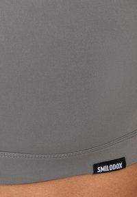 Donkergrijze sportbroek met een gladde textuur, voorzien van een gestikte zoom en een klein zwart label met witte tekst "SMILODOX."