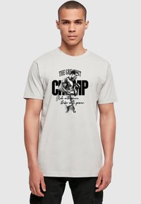 Light gray cotton t-shirt featuring a black and white graphic of a boxer with bold text “THE GREATEST CHAMP” above and a quote below.