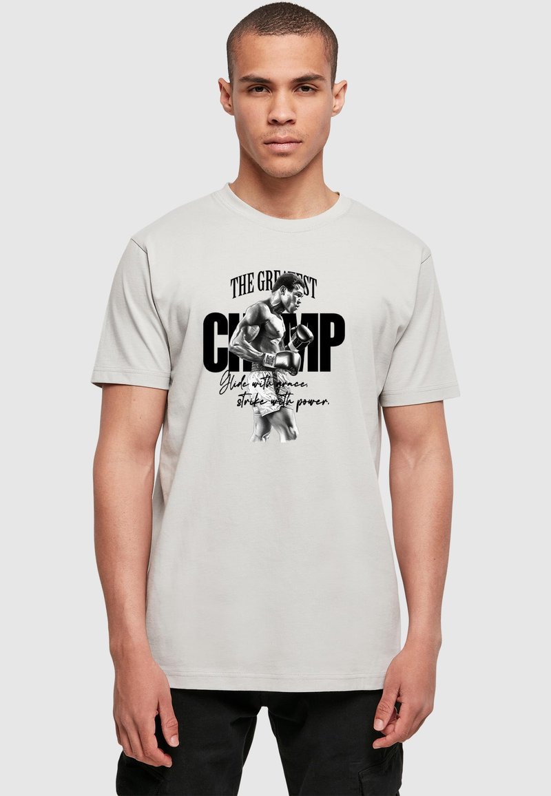 Light gray cotton t-shirt featuring a black and white graphic of a boxer with bold text “THE GREATEST CHAMP” above and a quote below.