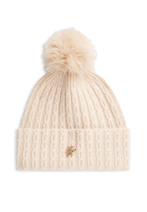 Bonnet d'hiver en maille crème avec motif torsadé, revers plié, détail monogramme doré, et gros pompon duveteux sur le dessus.