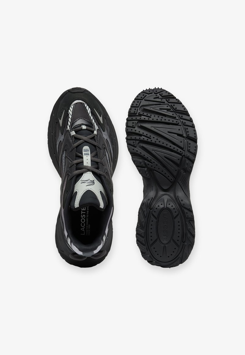 Schwarzer und grauer Lacoste-Sneaker, von oben und von der Sohle aus betrachtet, mit detailliertem Profilmuster und Logo auf der Zunge und der Sohle.