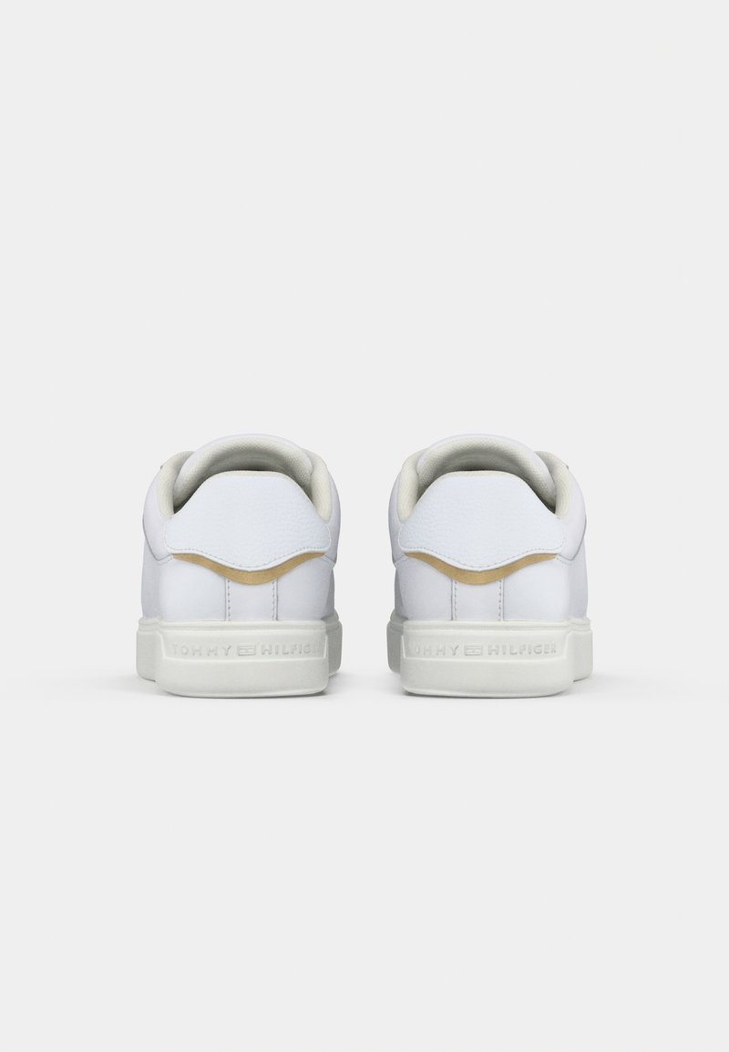 Paire de baskets blanches basses vues de dos, avec un accent beige au-dessus du talon et des semelles blanches de marque.