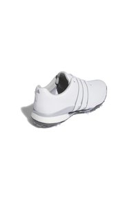 Bílé sportovní boty s hladkým povrchem, několika perforacemi, třemi vodorovnými pruhy a šedou podešví se hroty pro lepší trakci.