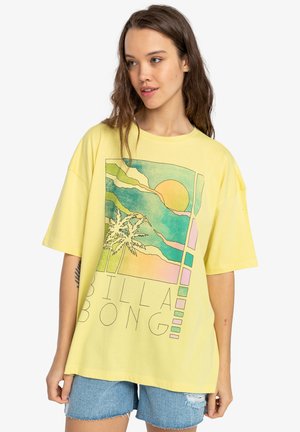 Gul oversized t-shirt med et farverigt grafik af en sol, palmer og abstrakte bølger, med teksten "BILLA BONG" nederst.