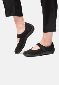 Schwarze Wildlederschuhe im Mary Jane-Design, mit gewelltem Rand, verstellbarem Riemen und einer gepolsterten Sohle für Komfort.