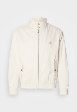 White lightweight jacket with a high collar, front zip closure, two side pockets, and elastic cuffs. Features a logo on the left chest.