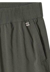 Elastyczny pas w oliwkowozielonych spodniach z małym srebrnym kwadratowym logo w pobliżu szwu kieszeni.