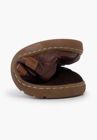 Pantofole in pelle marrone con un design flessibile, suola in gomma e dettagli cuciti. L'interno è realizzato in un morbido materiale scuro.