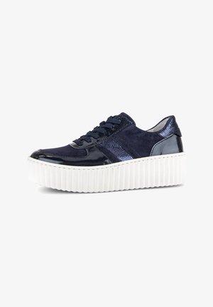 Navy blue sneaker with patent leather and suede upper, featuring a thick white rubber sole with ridges and textured accents on the heel.