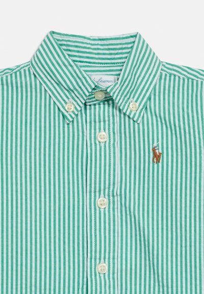 Πράσινο και λευκό κάθετα ριγέ πουκάμισο με κουμπιά και κεντημένο λογότυπο παίκτη πόλο στο στήθος, με λευκά κουμ πιά μπροστά.