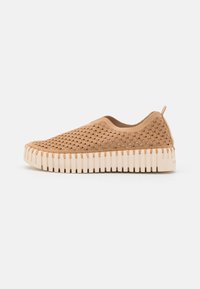 Beżowe buty slip-on z teksturowanym, plecionym wierzchem i białą, żłobioną podeszwą. Posiadają pętlę na pięcie ułatwiającą zakładanie.