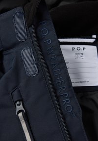 Mørkeblå jakke med lynlås og velcro-lukninger, mærket "P.O.P WEATHER PRO" og tøjlabel, der viser størrelsen 92 til alderen 1,5-2 år.