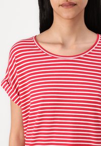 T-shirt rayé rouge et blanc avec un col rond et des manches courtes retroussées, fabriqué en tissu doux, présentant des motifs horizontaux réguliers.