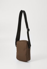 Geantă de umăr din material maro, cu formă rectangulară, față plată și curea neagră ajustabilă. Material texturat cu un design simplu și fără elemente de prindere vizibile.