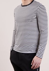Långärmad tröja med rundad halsringning i horisontella svartvita ränder, tillverkad av mjukt bomullstyg, med en kroppsnära passform.