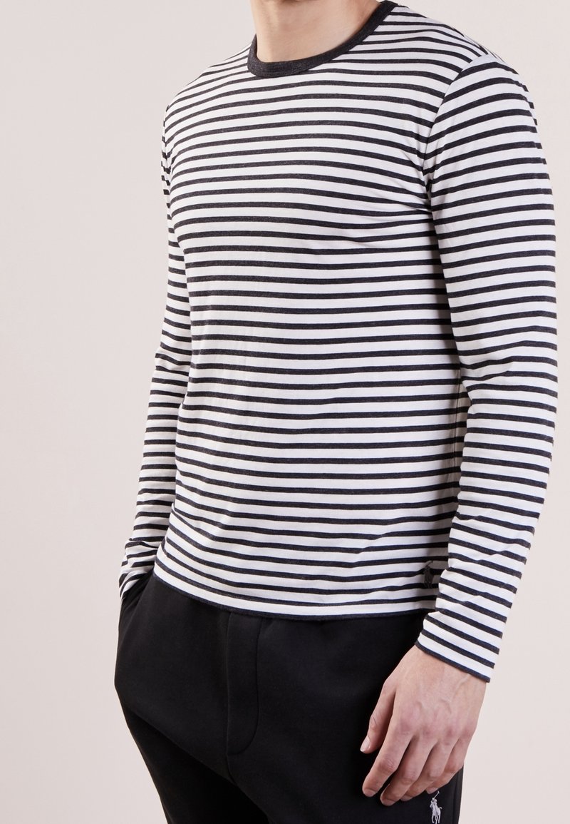 Långärmad tröja med rundad halsringning i horisontella svartvita ränder, tillverkad av mjukt bomullstyg, med en kroppsnära passform.
