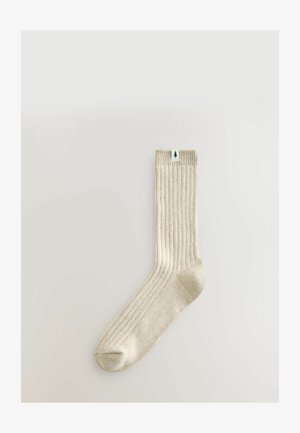 Kermankotoinen ribbiskoska, jossa on pehmeä rakenne ja vihreä puulogokyltti ylhäällä. Standardsukkamuoto, jossa on vahvistettu varvas.