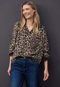 Leopardprint, gennemsigtig bluse i stof med V-hals og rynkede ærmer, sat sammen med mørkeblå jeans. Simpelt, afslappet design.