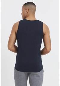 Navyblaues Tanktop aus Baumwolle, mit rundem Halsausschnitt und ärmellosem Design, kombiniert mit grauen Jogginghosen.