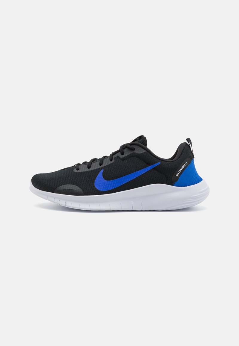 Chaussures de sport noires avec un dessus texturé, swoosh bleu de Nike et semelle blanche. Équipées de lacets et d'une languette à l'arrière.