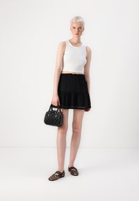 Hvit cropped tank top, svart blonde lagdelt skjørt, svart teksturert håndveske og dyreprint leiligheter. Fokuser på enkelhet og definerte former.