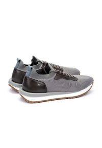 Zapatillas de malla grises con acentos de cuero marrón oscuro, suela gris y tapón de talón en un azul claro que contrasta. Presentan un diseño clásico de cordones.