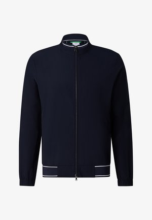 Marineblå lynlåsskjortejakke med ståkrave, elastiske manchetter og hvide accentstriber på kanten mod en hvid baggrund.