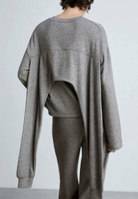 Grauer Hoodie mit übergroßer Passform und einem einzigartigen Rückenausschnitt. Der weiche, strukturierte Stoff geht in lange Ärmel über.