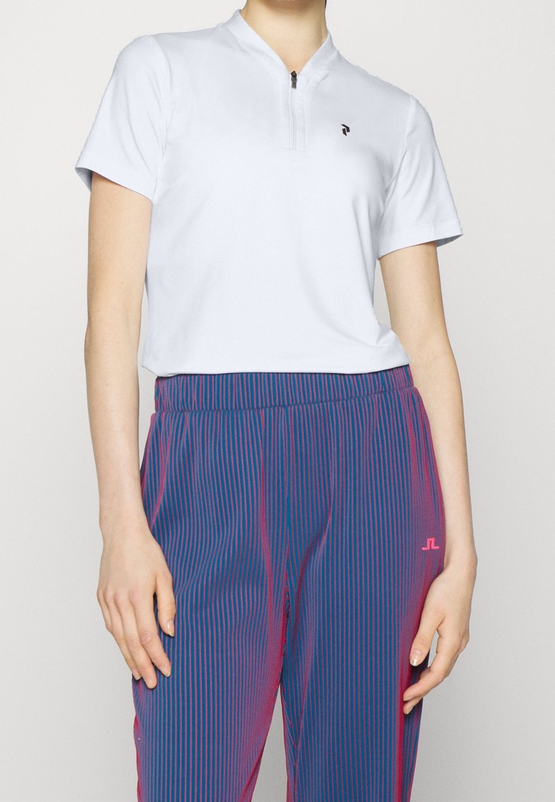 Haut bleu clair à manches courtes avec col mandarin et fermeture éclair, associé à un pantalon rayé bleu et rose doté d'une taille élastique.