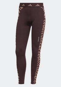 Leggings atletici marroni con una texture liscia, una vestibilità aderente e dettagli in stampa animale lungo il lato in beige chiaro.