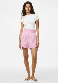 Rožinės languotos šortai su elastine juosmeniu, raišteliais ir patogiu pritaikymu; derinami su paprasta balta trumpomis rankovėmis marškinėliais.