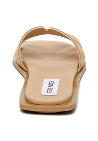 Sandale tongs beige avec une conception à une seule sangle, texture lisse, semelle plate et une étiquette de marque sur la semelle.